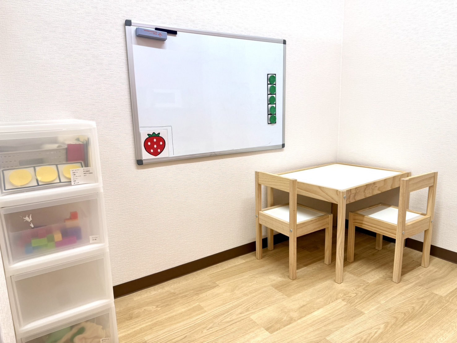 いちごの個室。ホワイトボードと、子ども用の机といすが置かれている