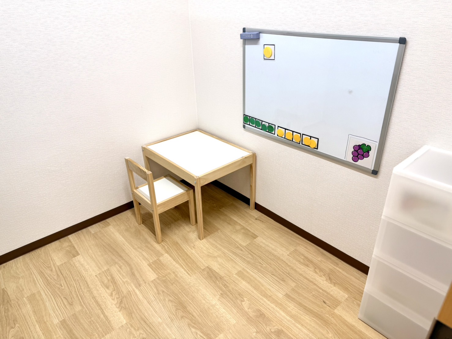 ぶどうの個室。ホワイトボードと、子ども用の机といすが置かれている